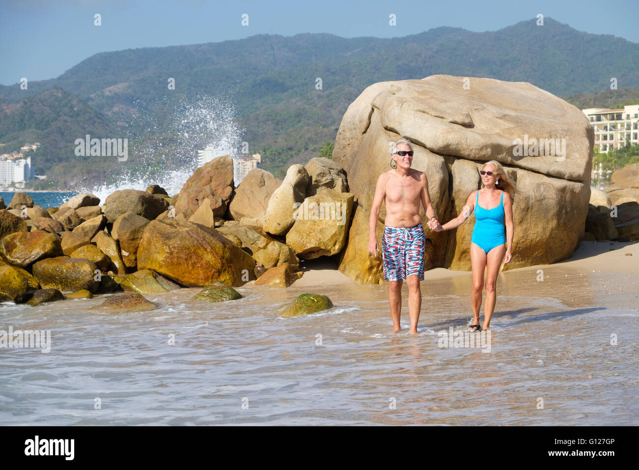 Senior man and woman enjoying retirement when walking at a beach in Mexico. Stock Photo