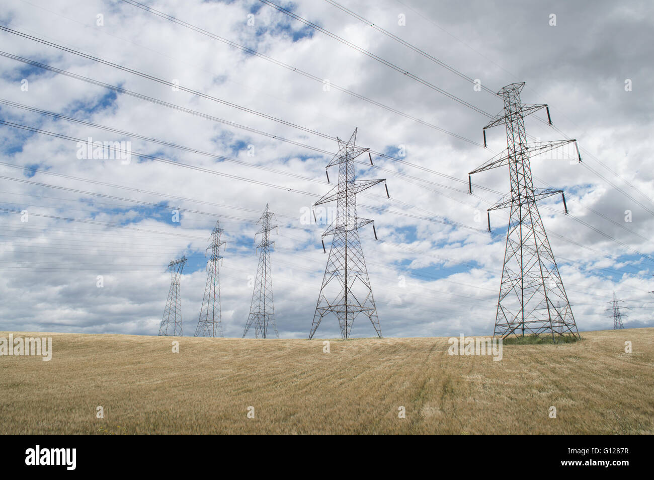 High-voltage towers on cloudy sky background Stock Photo - Alamy