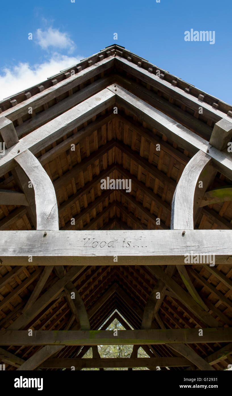 Timber framed shelter with the words WOOD IS... carved onto a cross beam. Westonbirt Arboretum, Gloucestershire, England Stock Photo