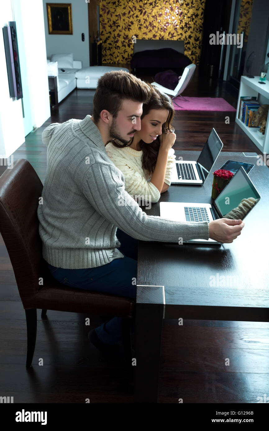 A young couple using in the evening their laptop computers at home and ...