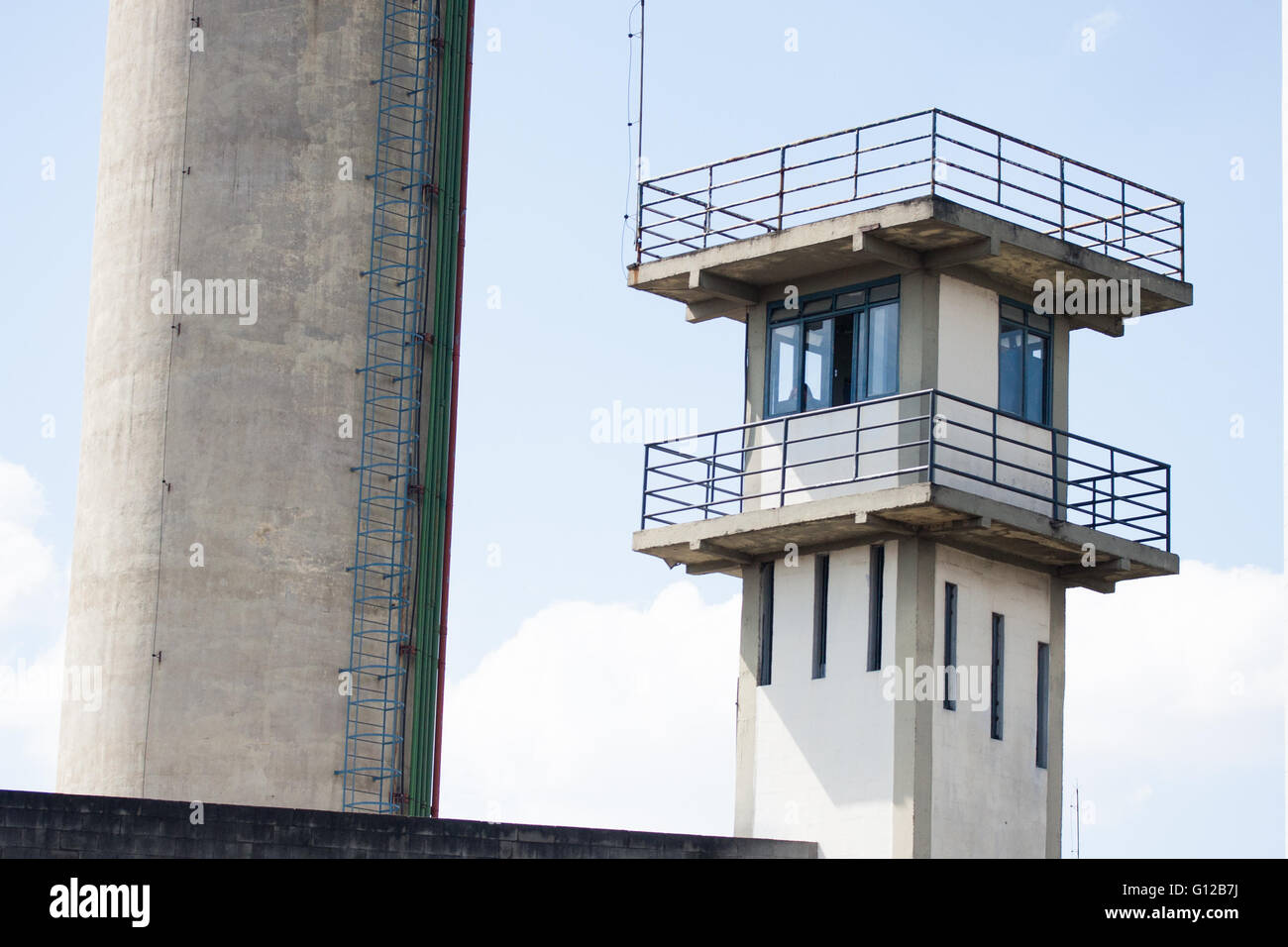 Prison security tower and metal ladder with blue sky and white clouds behind Stock Photo
