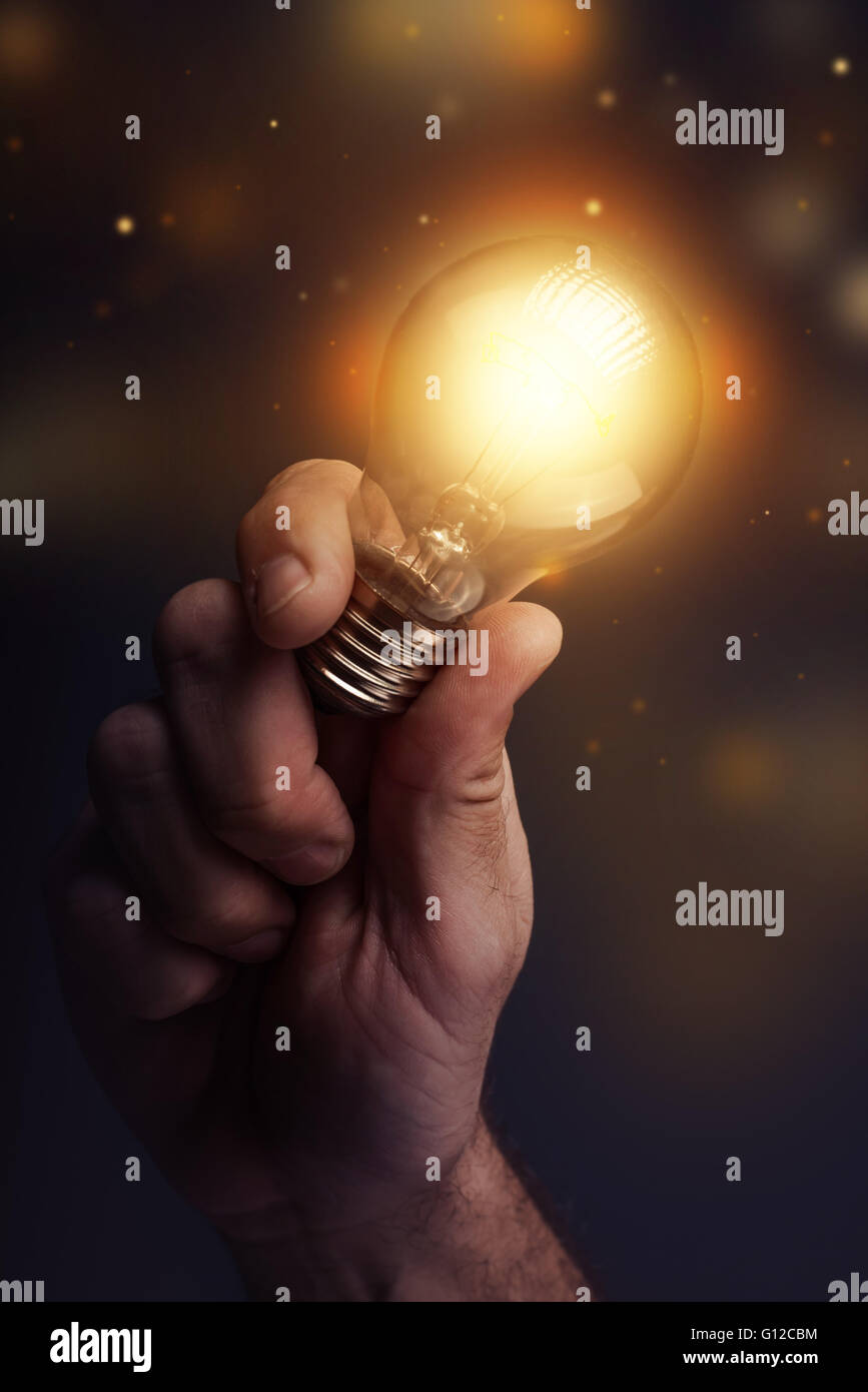 Creative energy and power of new ideas, hand holding light bulb, retro toned image, selective focus. Stock Photo