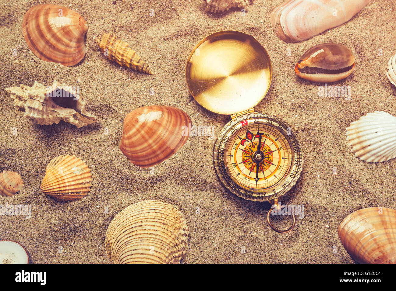Top view of vintage compass and sea shells on sandy beach, navigational ...
