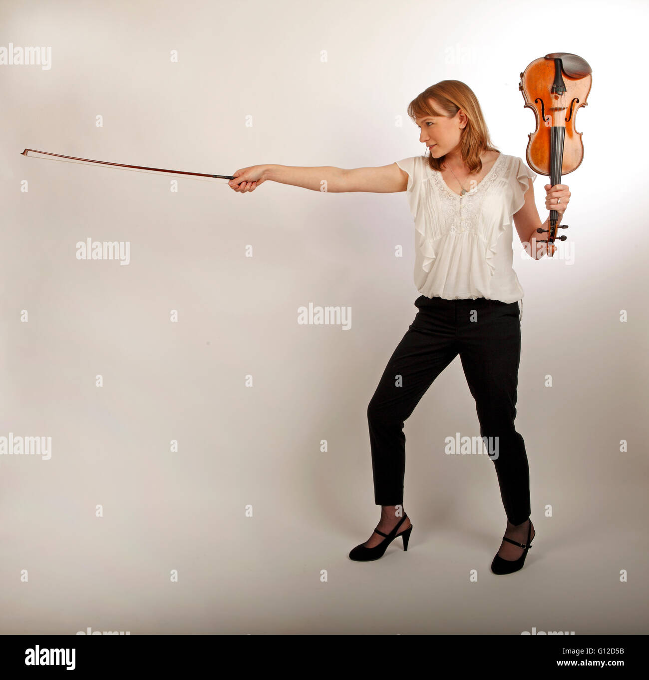 young woman holding a violin and bow like a sword and shield Stock Photo
