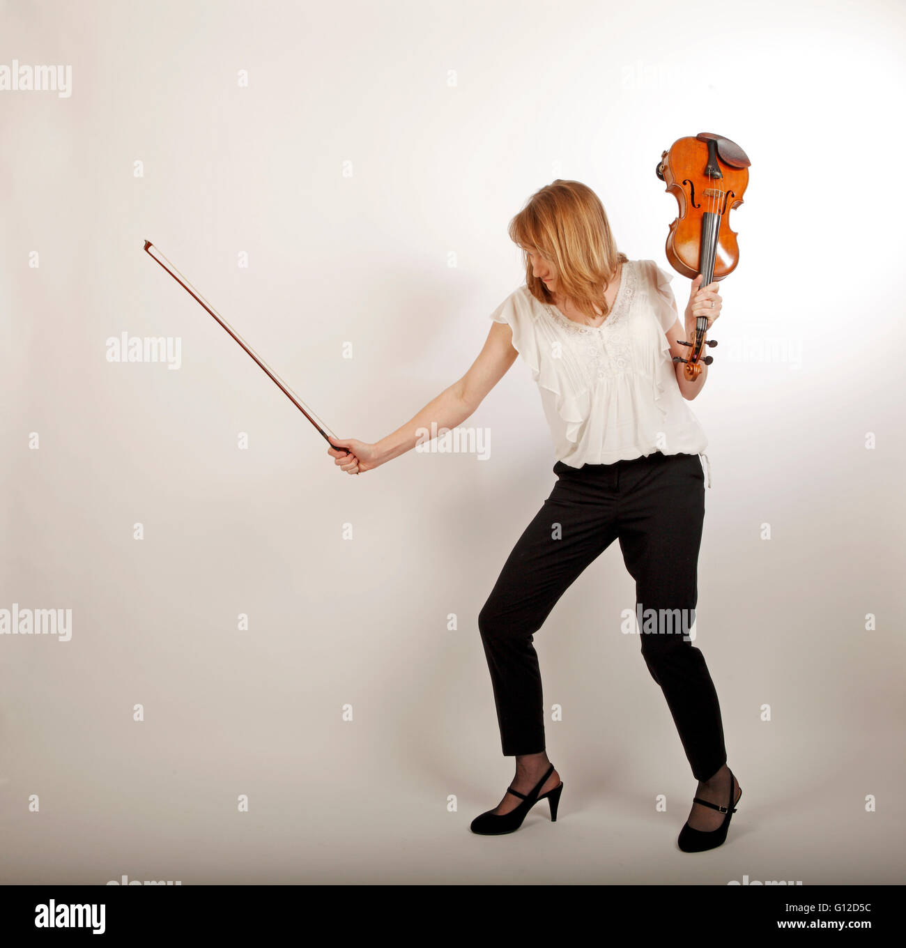 classical dance music, young woman holding a violin and a bow and dancing Stock Photo