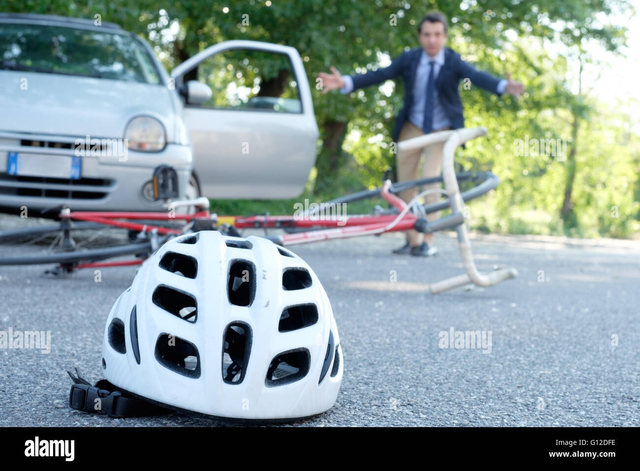 driver coming out from his car to assist aching man after bicycle accident on the asphalt Stock Photo