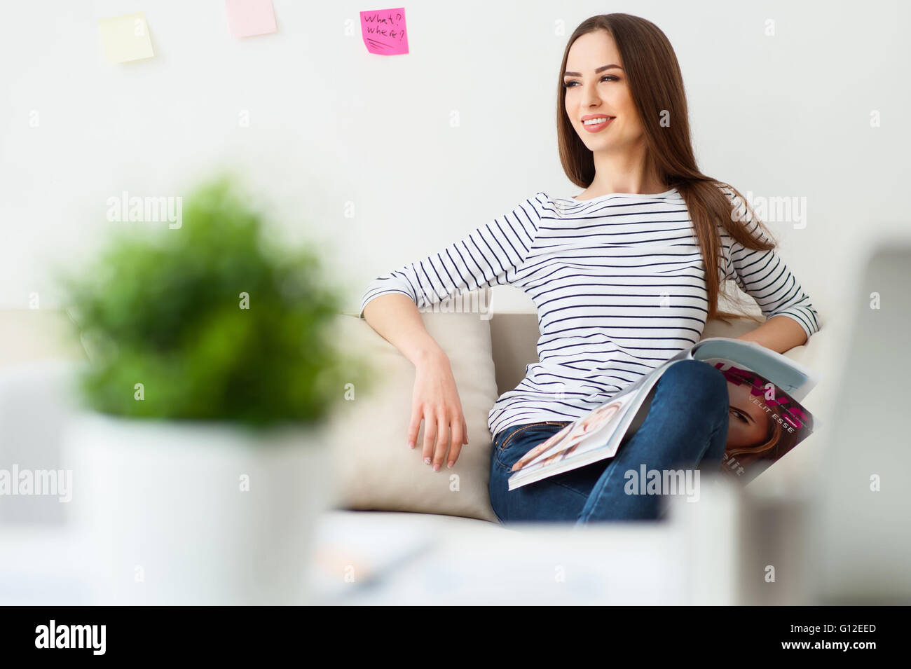 Cheerful woman sitting on the couch Stock Photo - Alamy