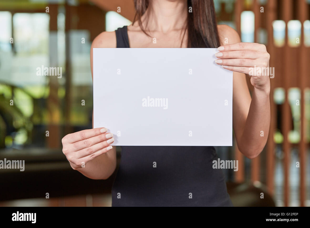 Young caucasian woman holding white sheet of paper Stock Photo