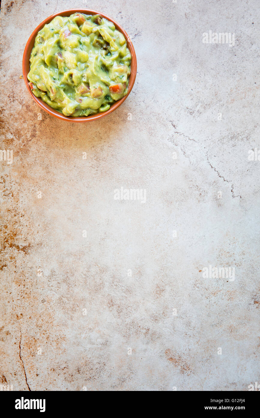 Bowl of fresh guacamole  n stone surface with copy space and viewed from above. Stock Photo