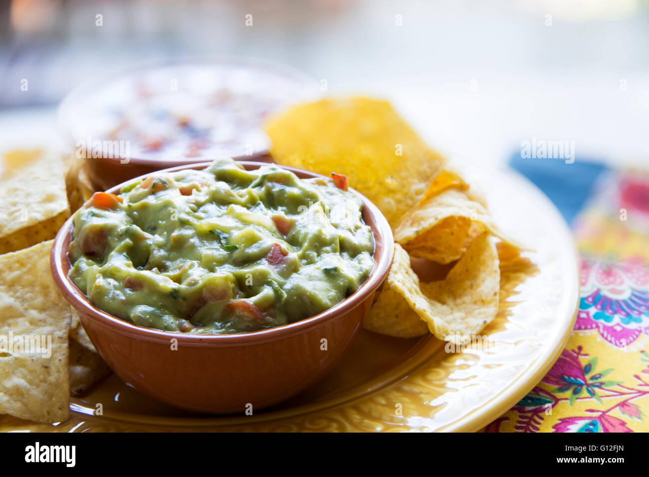 Fresh guacamole in a bowl with tortilla chips Stock Photo