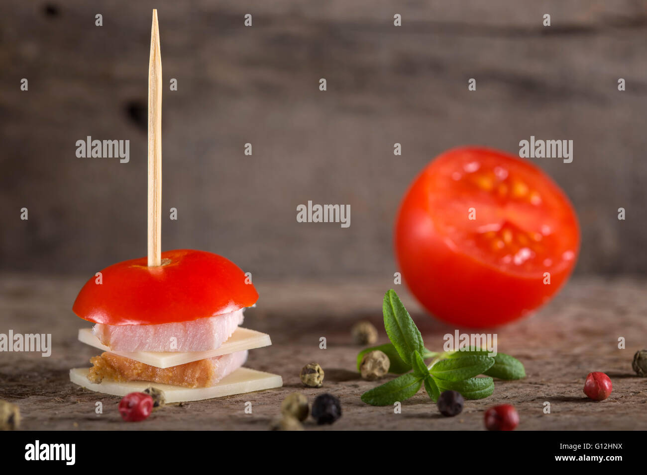 Mini ham and cheese appetizer with tomato and spices over wooden background Stock Photo