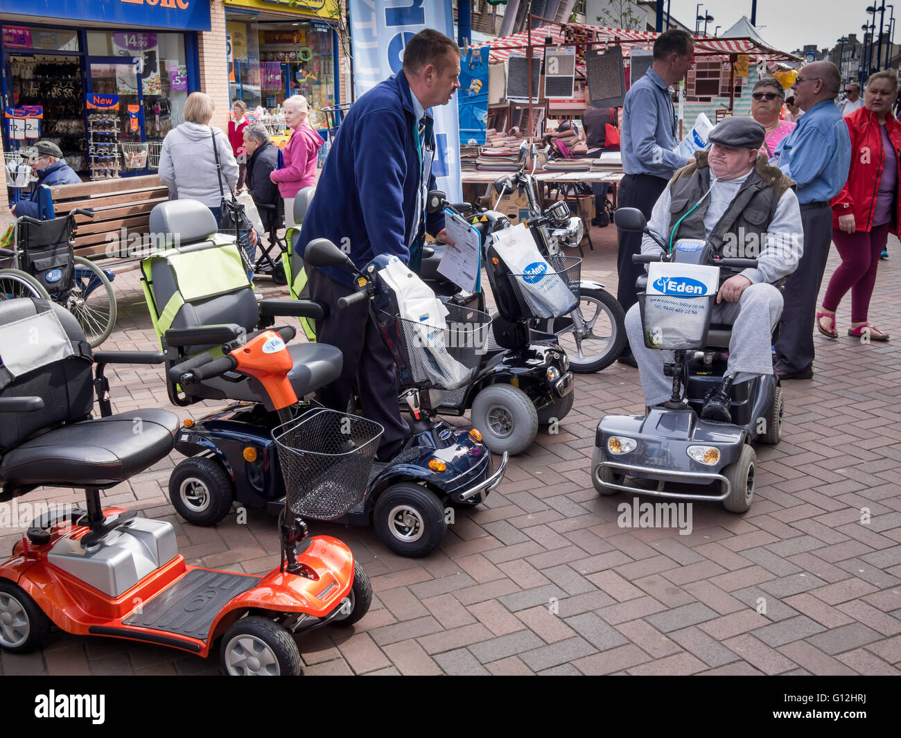 Display of Mobility Scooters for disabled people at the Weekly Market in Redcar Cleveland salesman talking to a scooter user Stock Photo