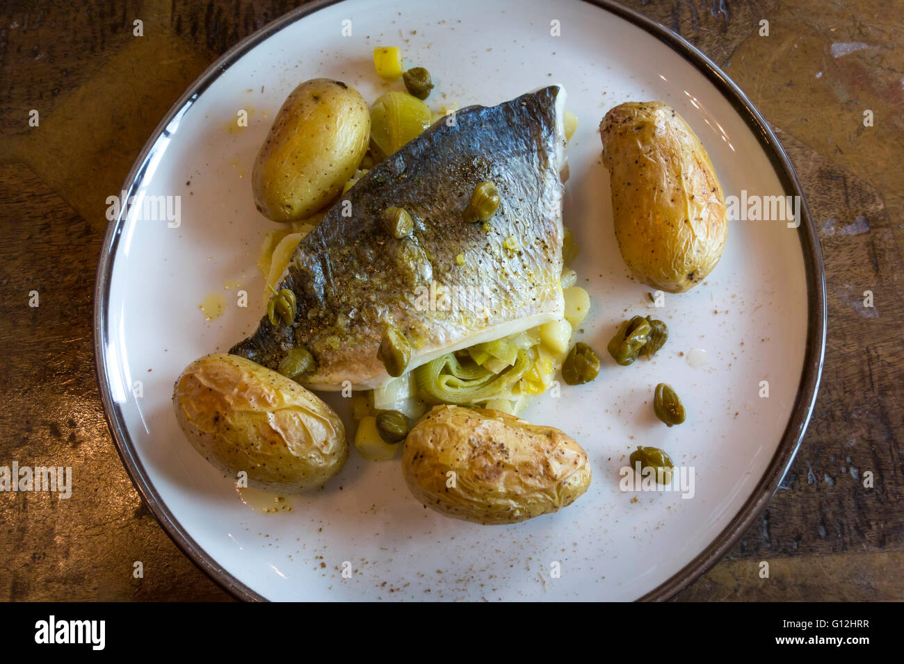 Café grilled Sea Bream with roast new potatoes buttered leeks fennel butter and capers at