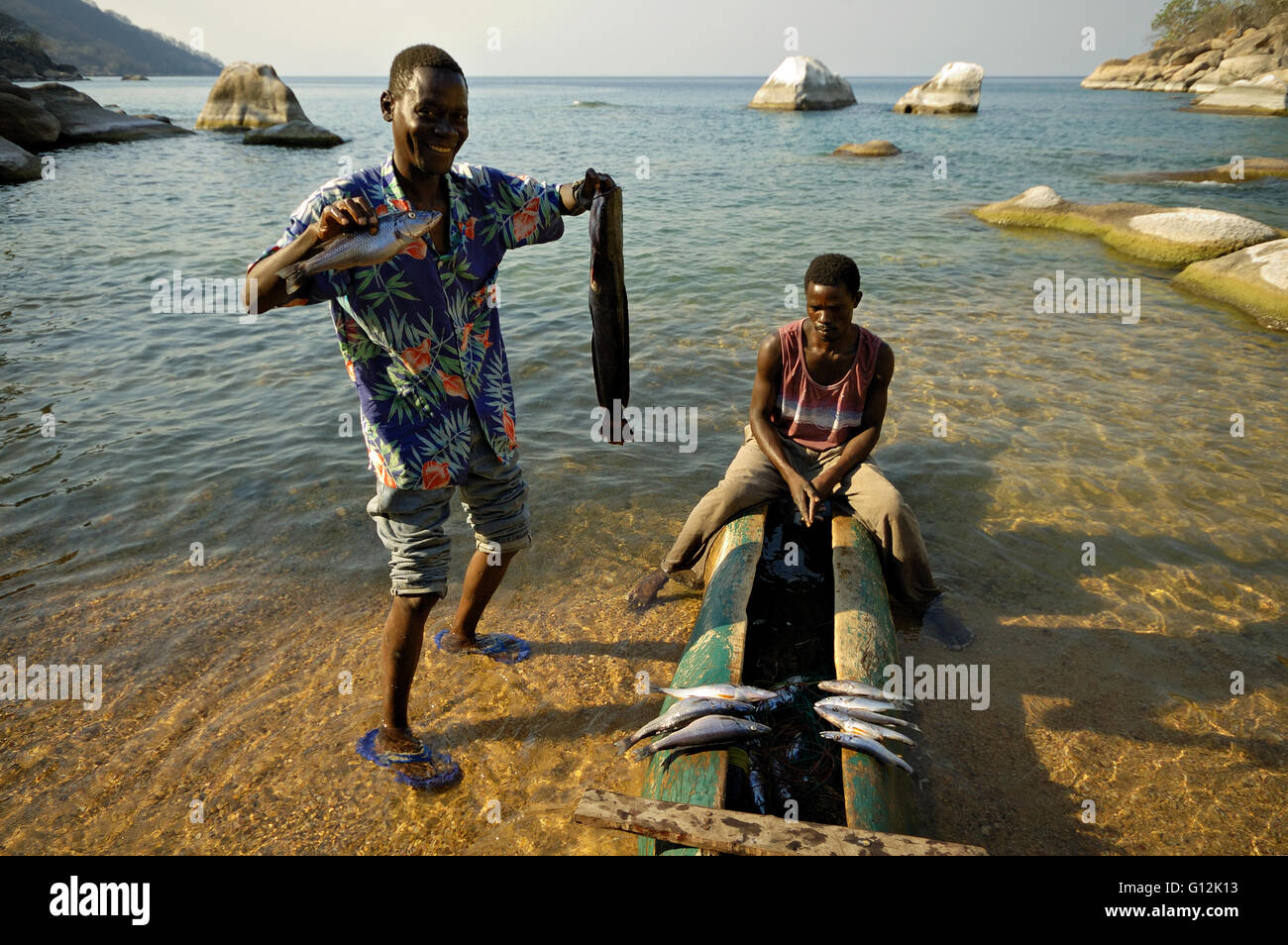 Fishermen with a dugout canoe showing fish on the beach in Ilala Gap, Lake Malawi National Park Stock Photo