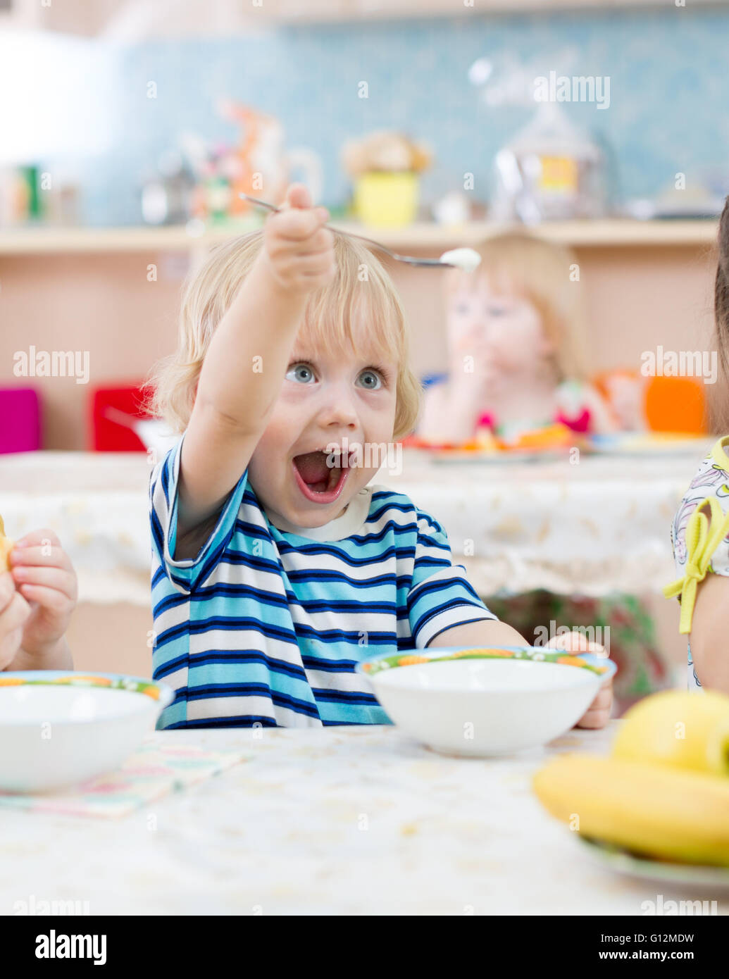 Funny kid playing during meal in kindergarten Stock Photo