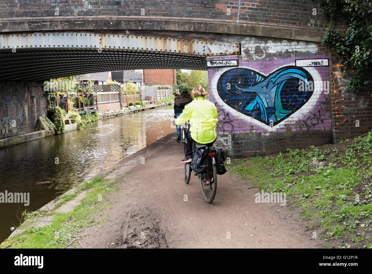 Two women cycling on the Grand Union Canal tow path, England, UK. Stock Photo