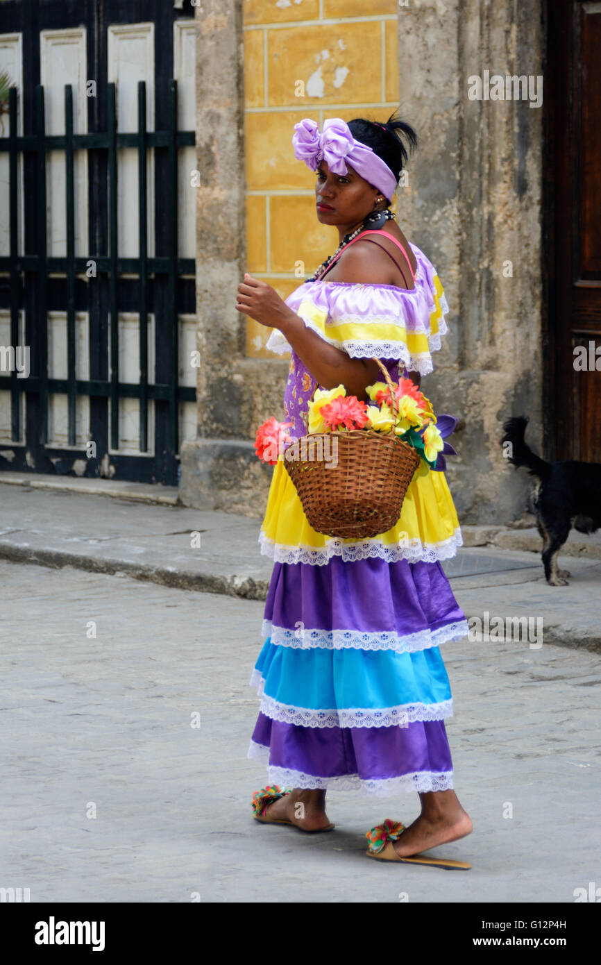 A flower seller wearing traditional costume walks along the street in Old Havana, Havana, Cuba Stock Photo