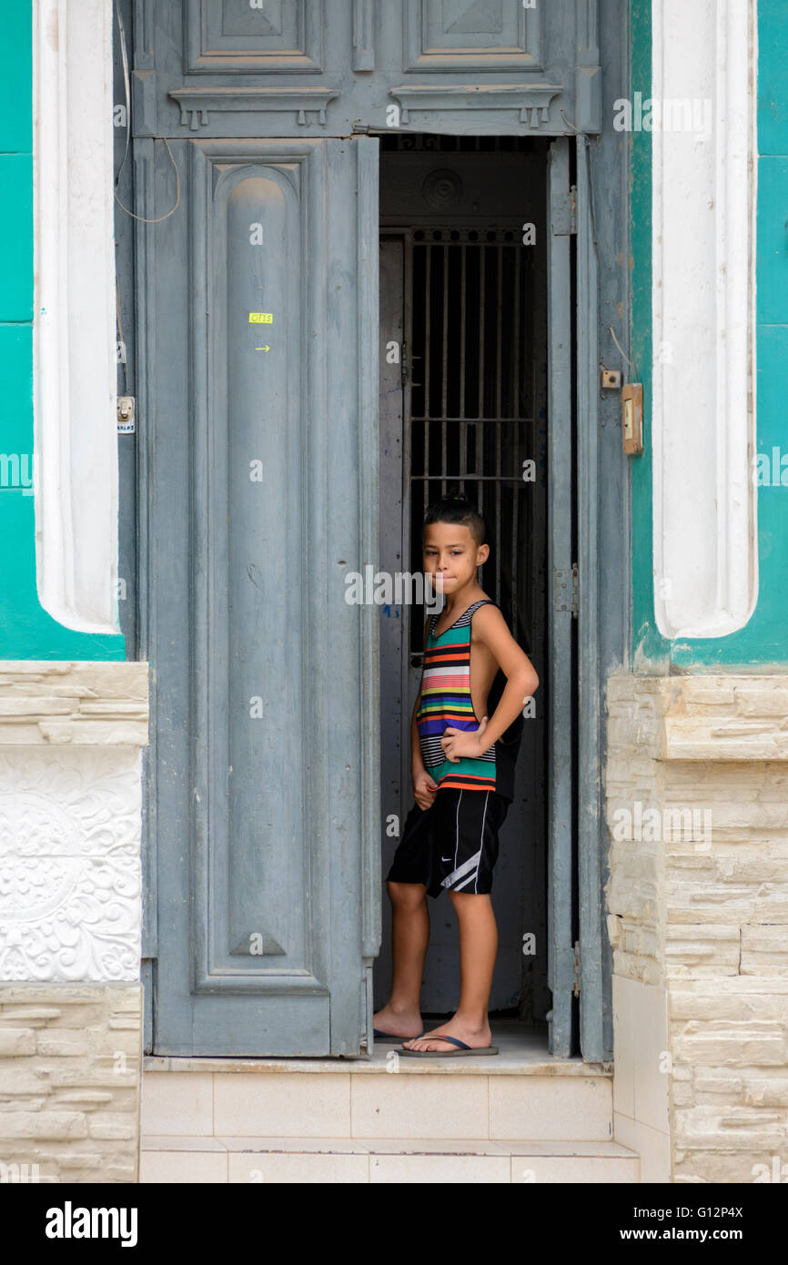 A young boy stands in a the doorway of a house in Central Havana, Havana, Cuba Stock Photo