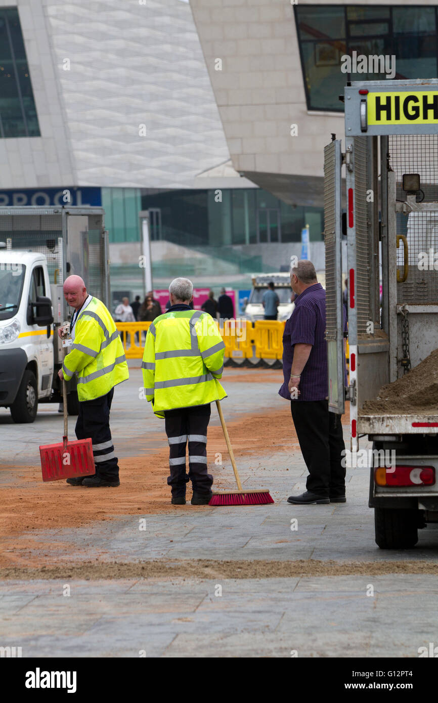 Street cleaners using sand to soak up water from burst main, Liverpool, Merseyside, UK Stock