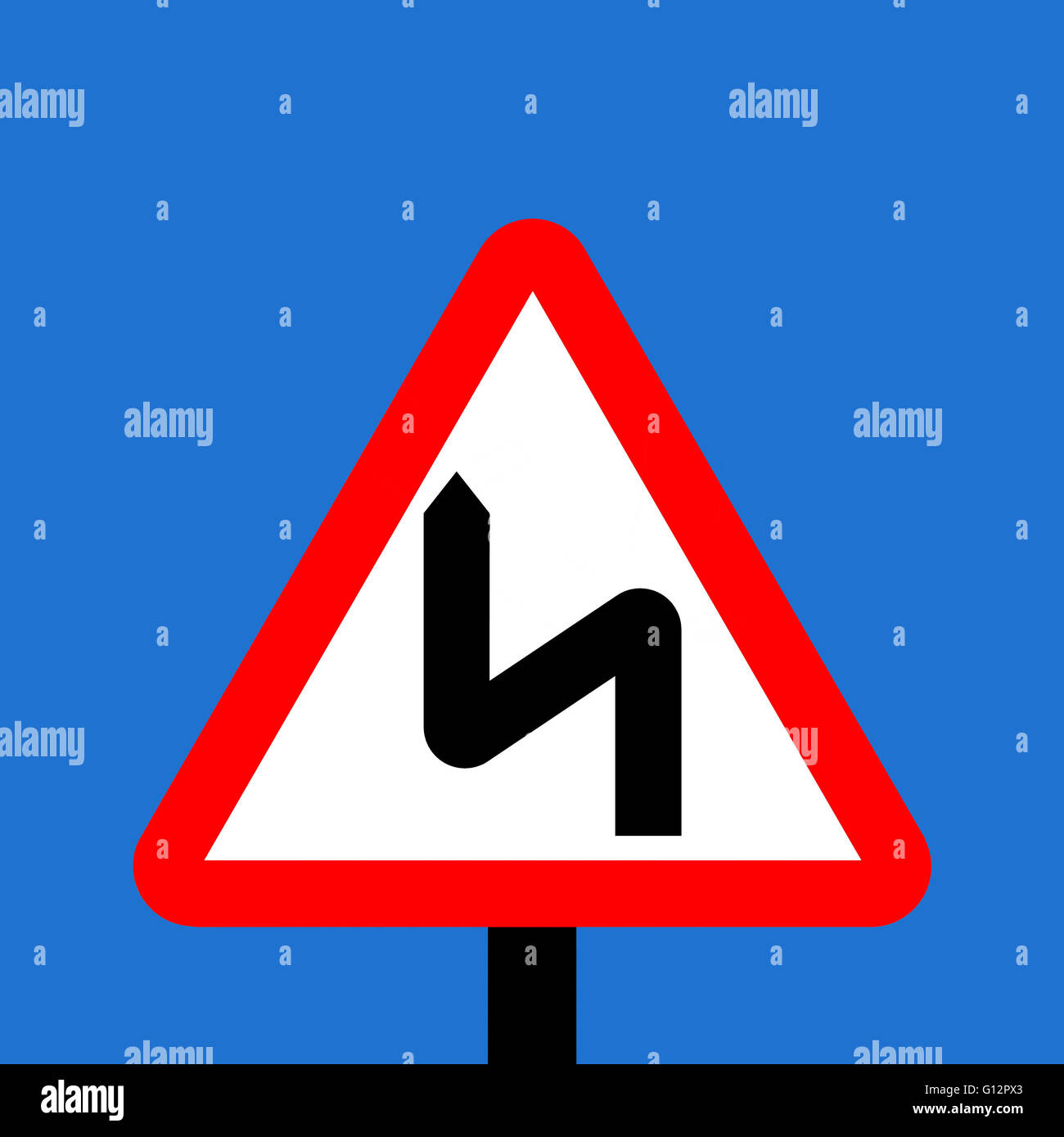Warning triangle Double bend first to left sign Stock Photo