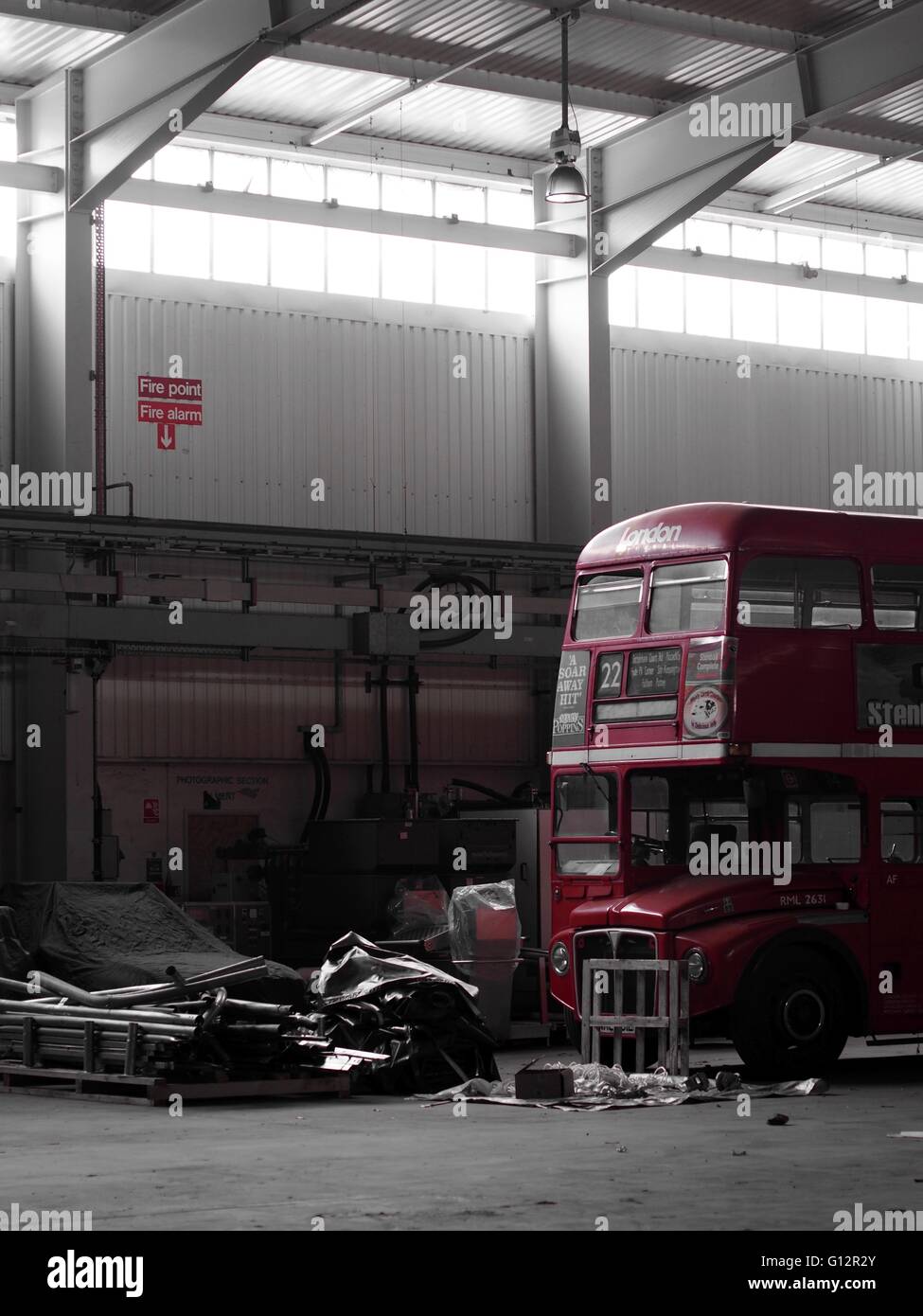 London Routemaster Bus abandoned in a hangar surrounded by junk Stock Photo