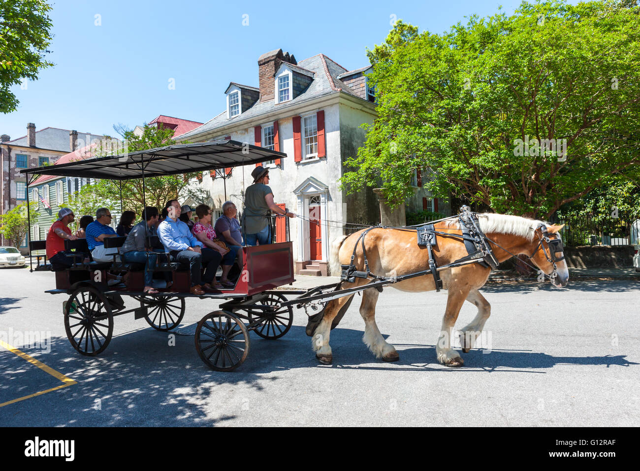 Tourists take a horse-drawn carriage tour past Antebellum homes in historic Charleston, South Carolina. Stock Photo