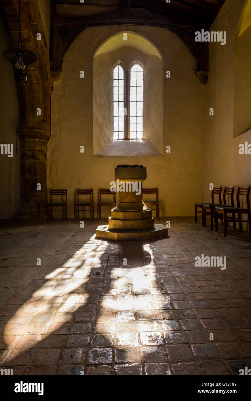Sunlight streams in through a window & iluminates the font in All Saints Church, Burton Dassett.  UK Stock Photo
