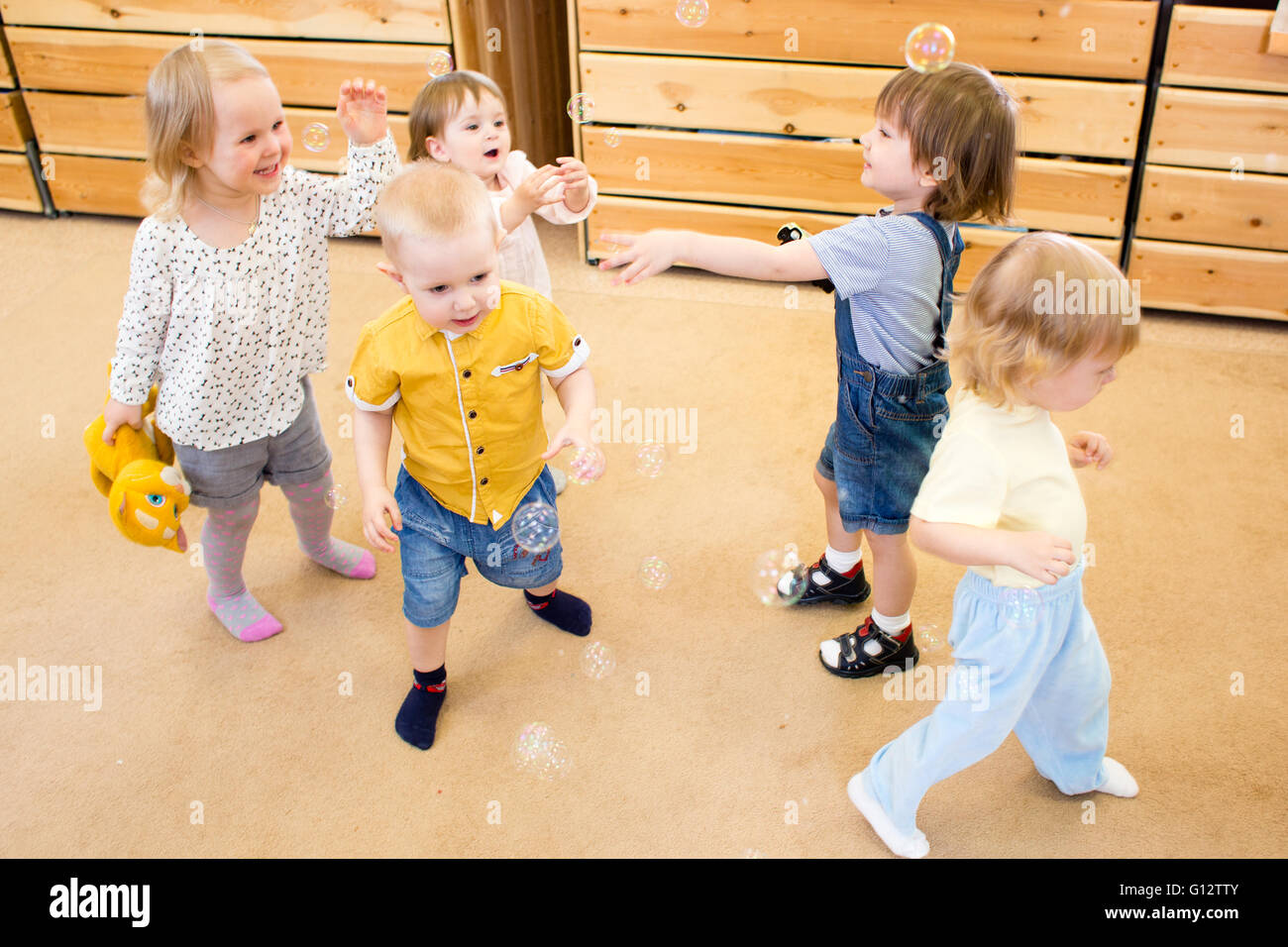 Children playing with soap bubbles in kindergarten Stock Photo