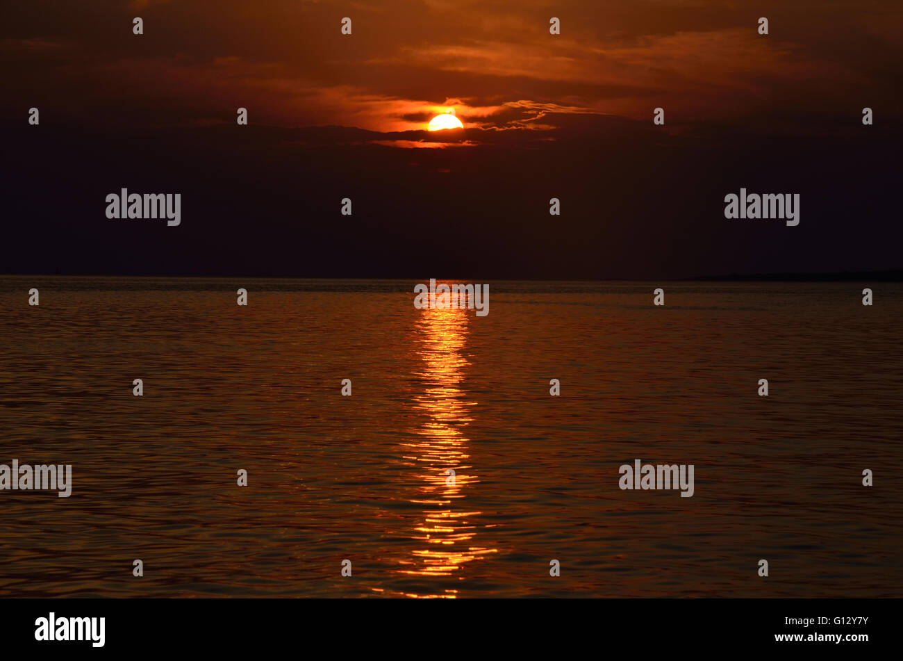 Sun is setting above the sea leaving long reflection on water Stock ...