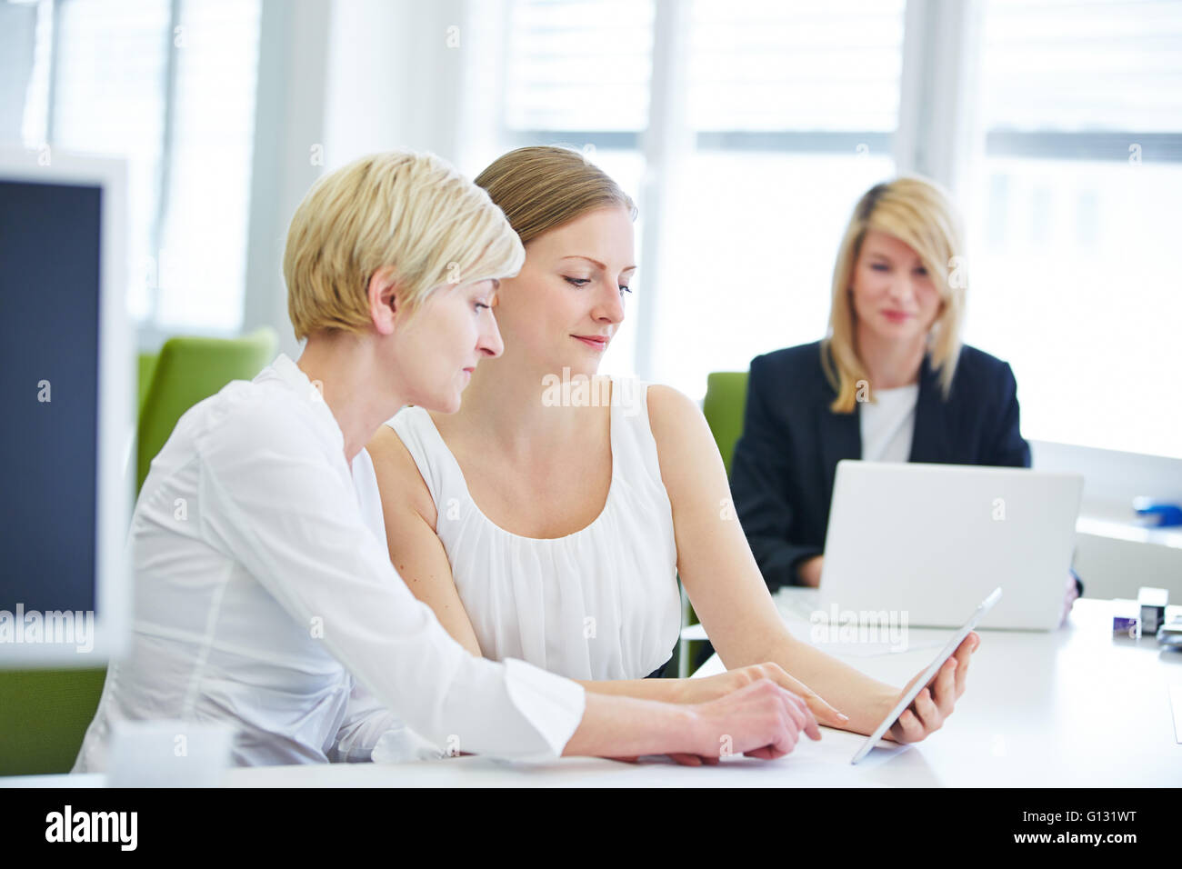 Two business women working with tablet computer at the desk in the office Stock Photo