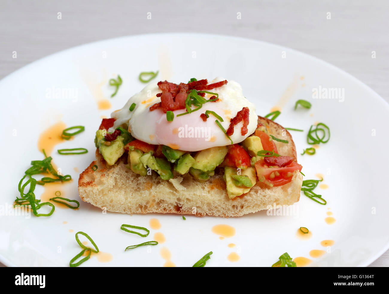 Poached eggs bacon tomatoes and avocado on toast Stock Photo Alamy