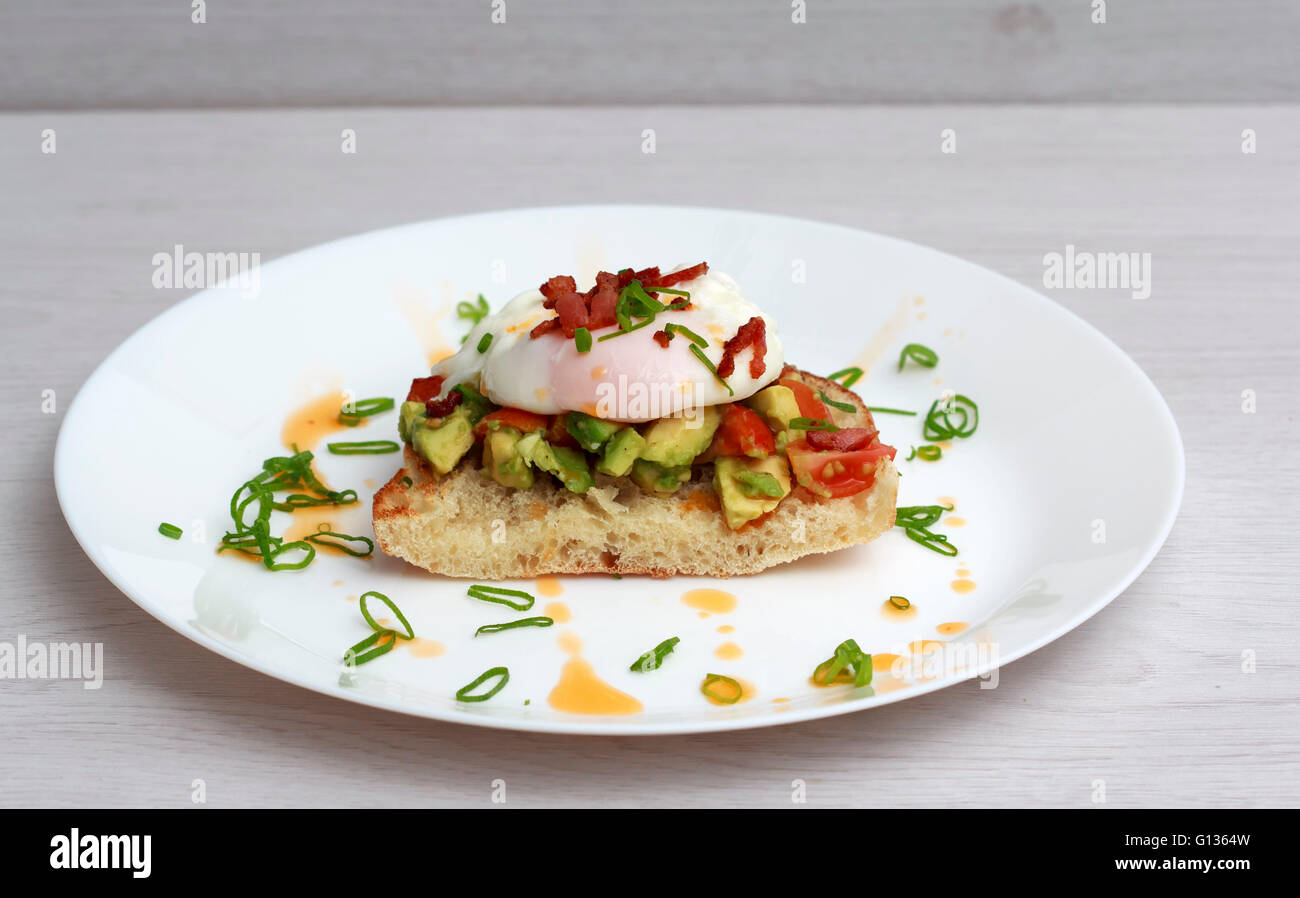 Poached eggs bacon tomatoes and avocado on toast Stock Photo Alamy