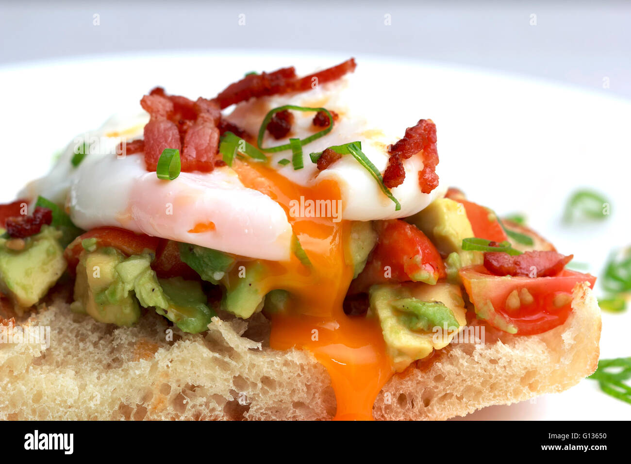 Poached eggs bacon tomatoes and avocado on toast Stock Photo
