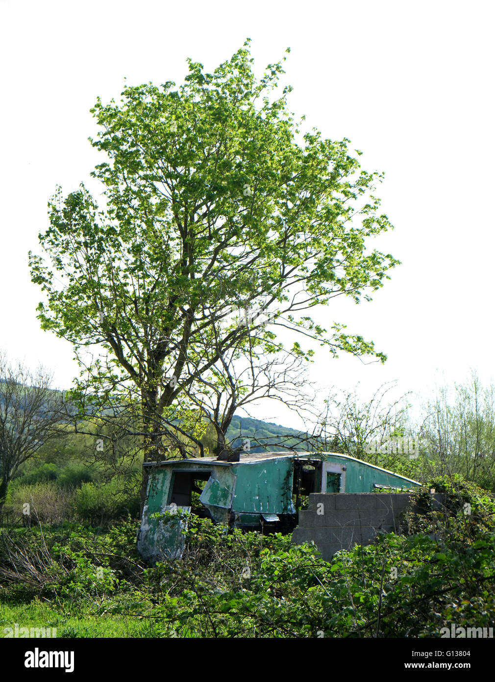 Old dilapidated touring caravan rotting in the corner of a field. 8th May 2016 Stock Photo