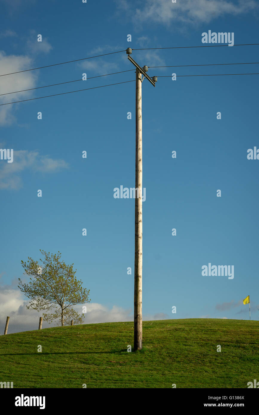 Simple wooden power lines pole and overhead electrical power lines in countryside Stock Photo