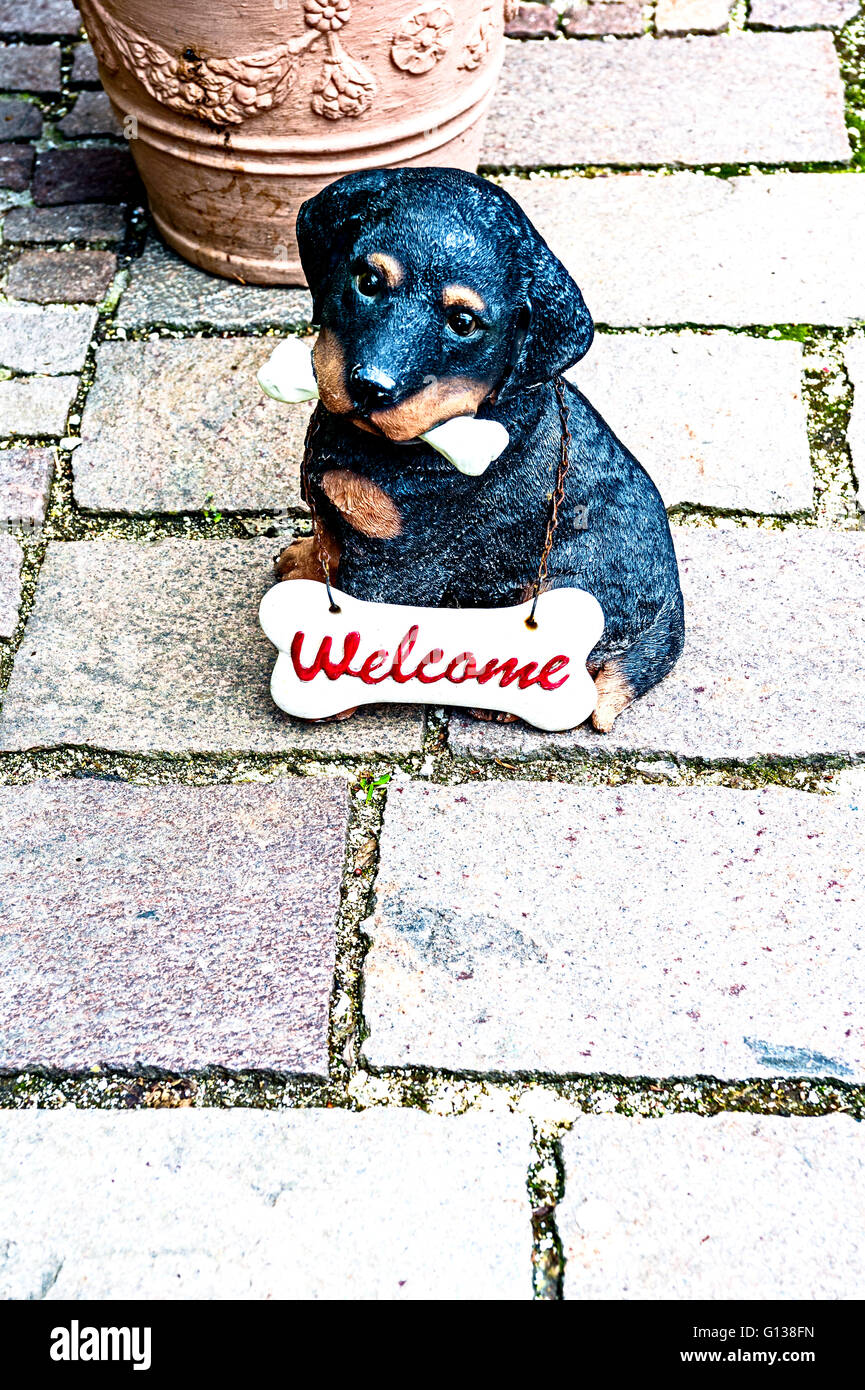 A little dog as fihure out of earthenware, wearing a sign 'Welcome' Stock Photo
