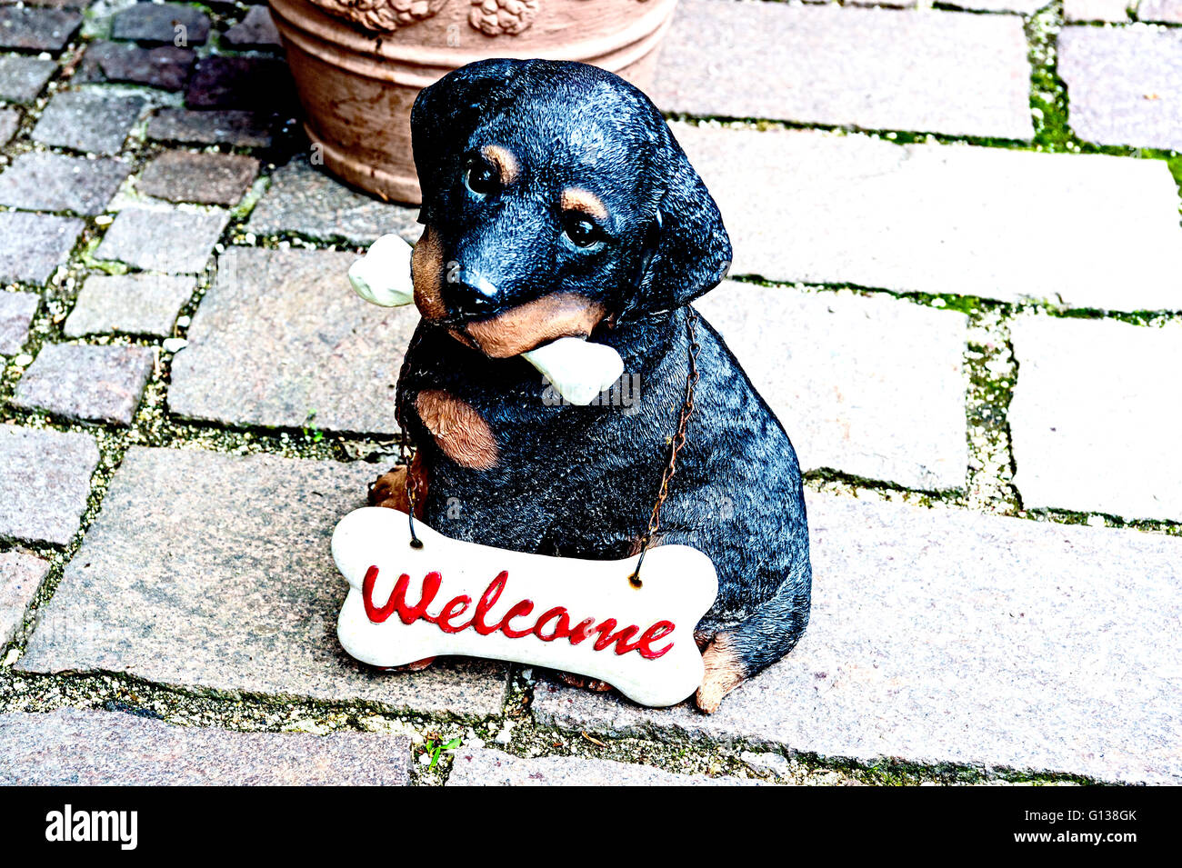 A little dog as fihure out of earthenware, wearing a sign 'Welcome' Stock Photo