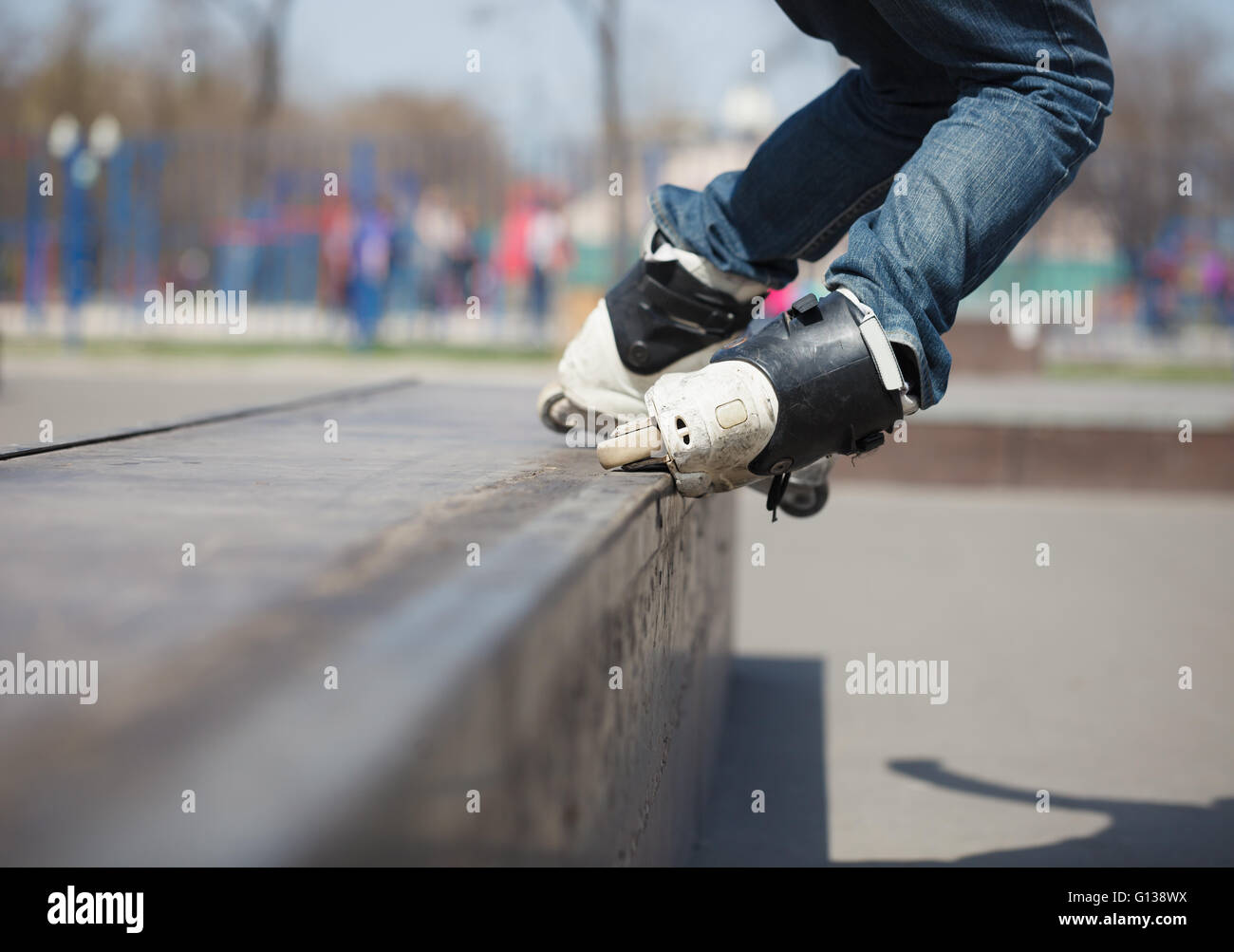 Rollerblader grinding on rail in skate park outdoors. Trick is