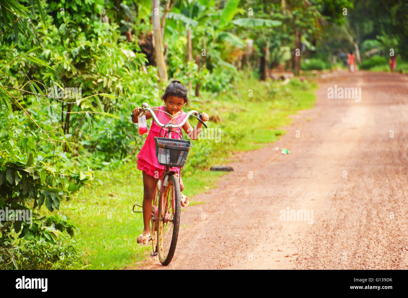 A small girl rides a large bike, Chi Phat, Cambodia Stock Photo
