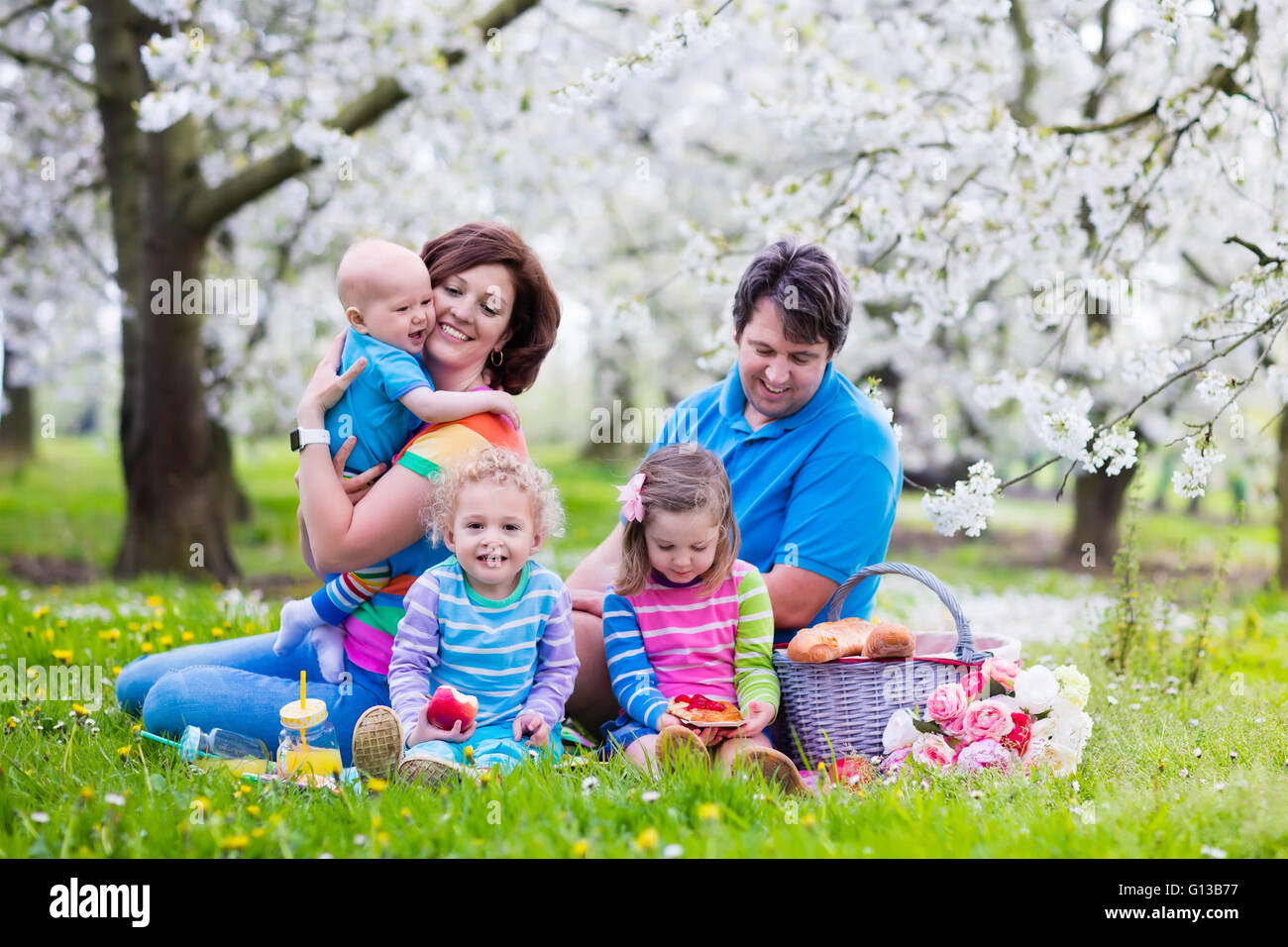 Big family with three little children eating lunch outdoors. Parents