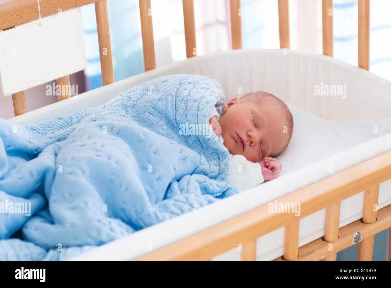 Newborn baby in hospital room. New born child in wooden cosleeper crib