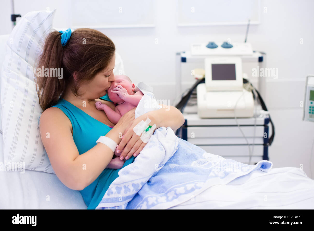 Mother giving birth to a baby. Newborn baby in delivery room. Mom holding her new born child after labor. Stock Photo