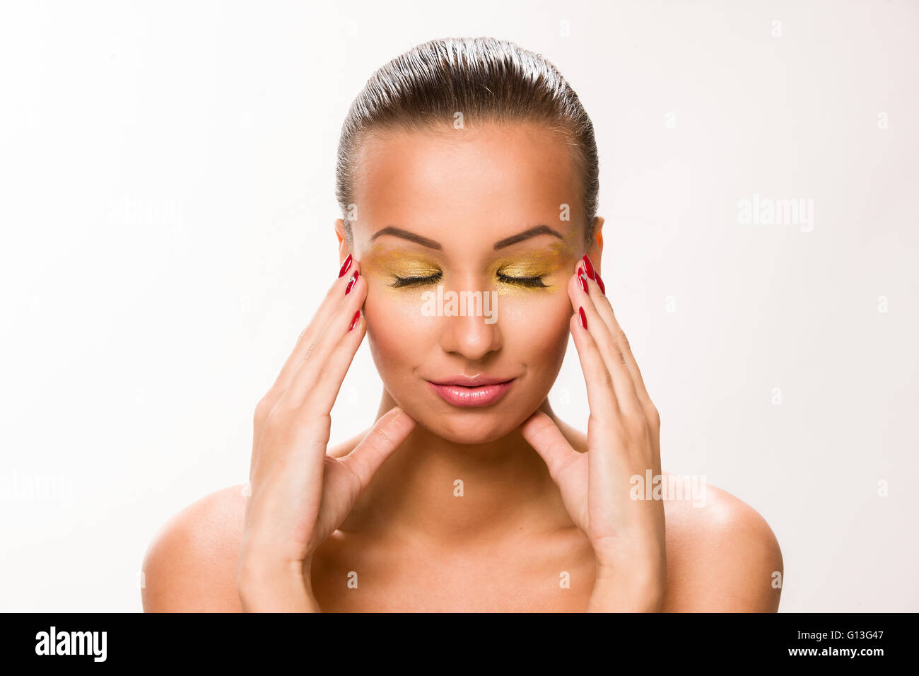 Gold make up. Brown sleek hair beautiful woman with hands on temples. Stock Photo