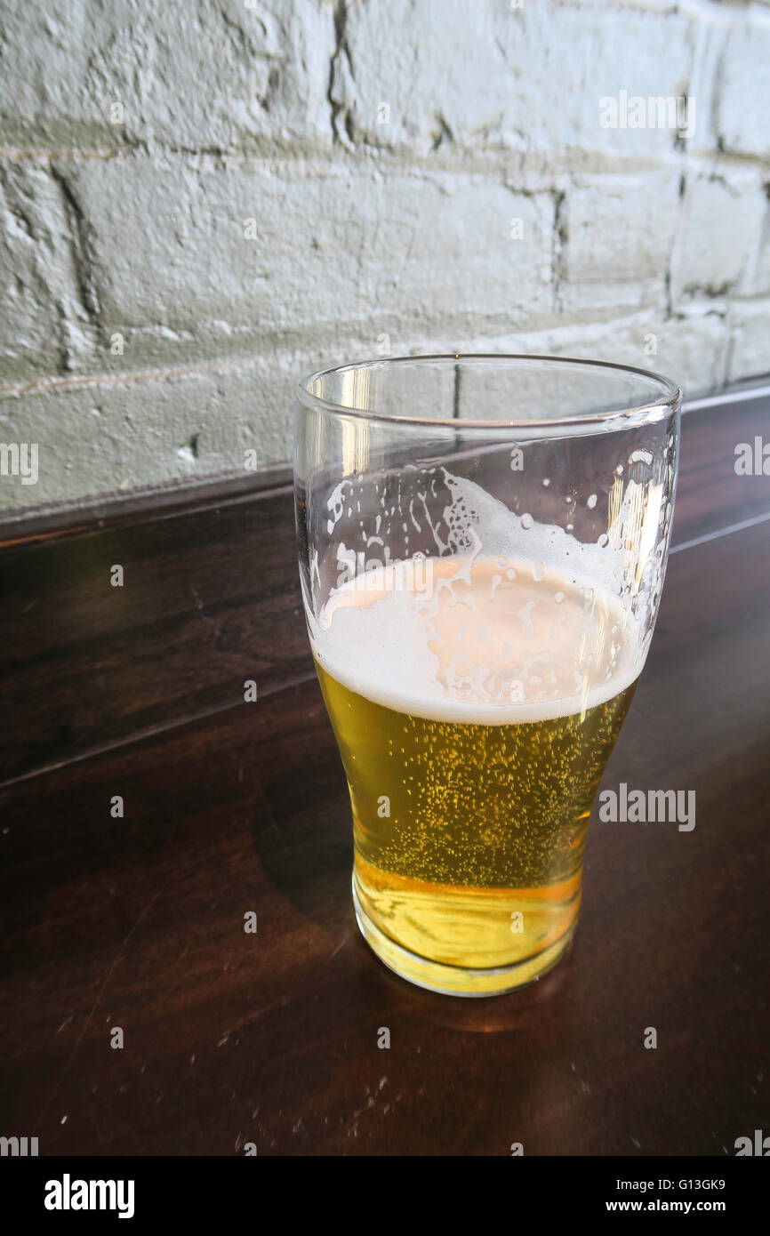 Half Consumed  Pint Glass of Beer on Bar, USA Stock Photo