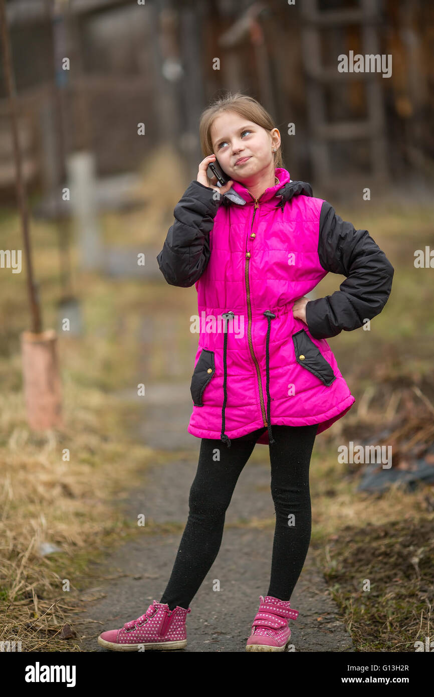 Little girl talking on mobile phone outdoors. Stock Photo