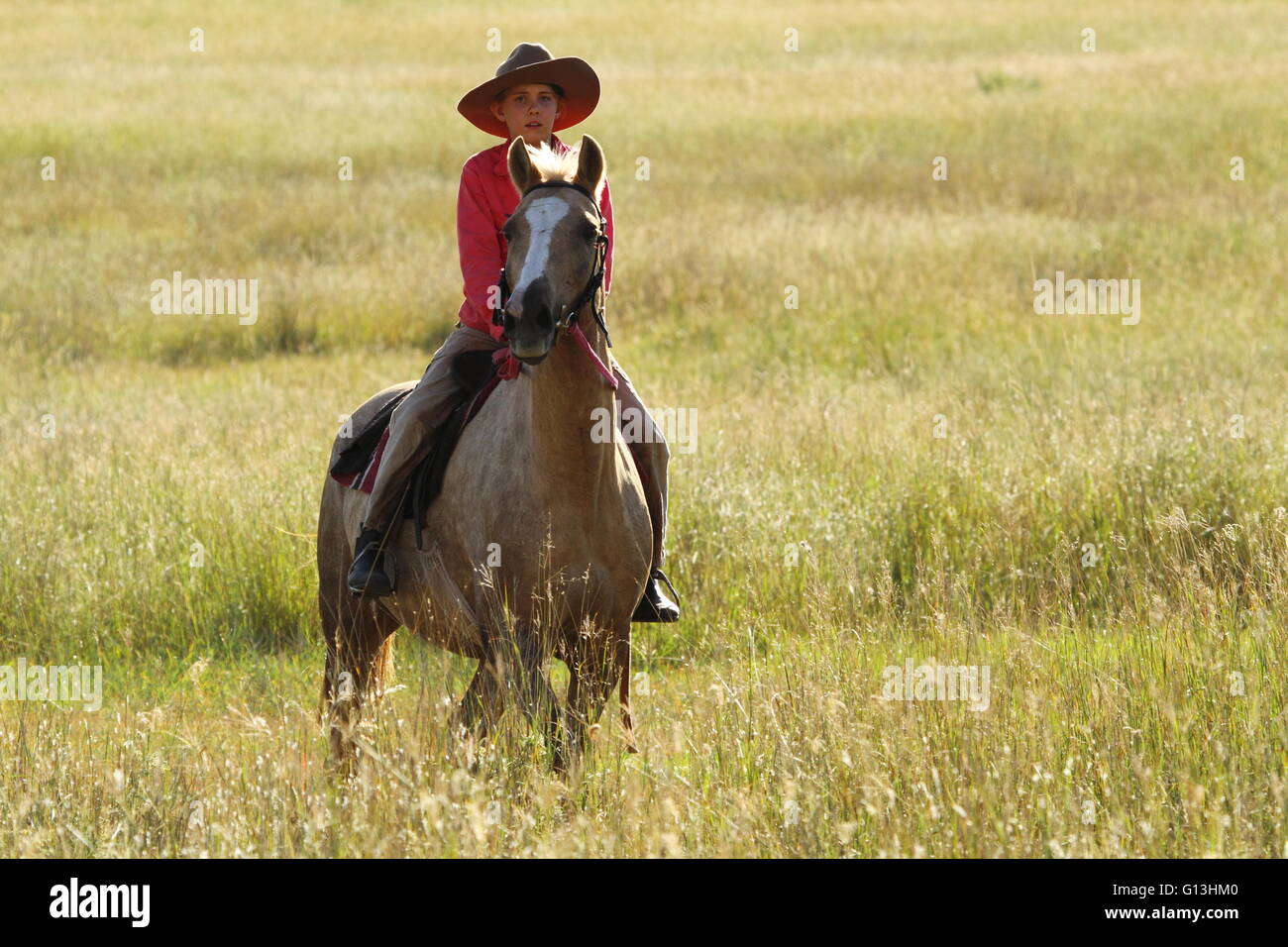 A young pre-teen girl sitting on her horse near Eidsvold, Queensland, Australia during a cattle drive. Stock Photo