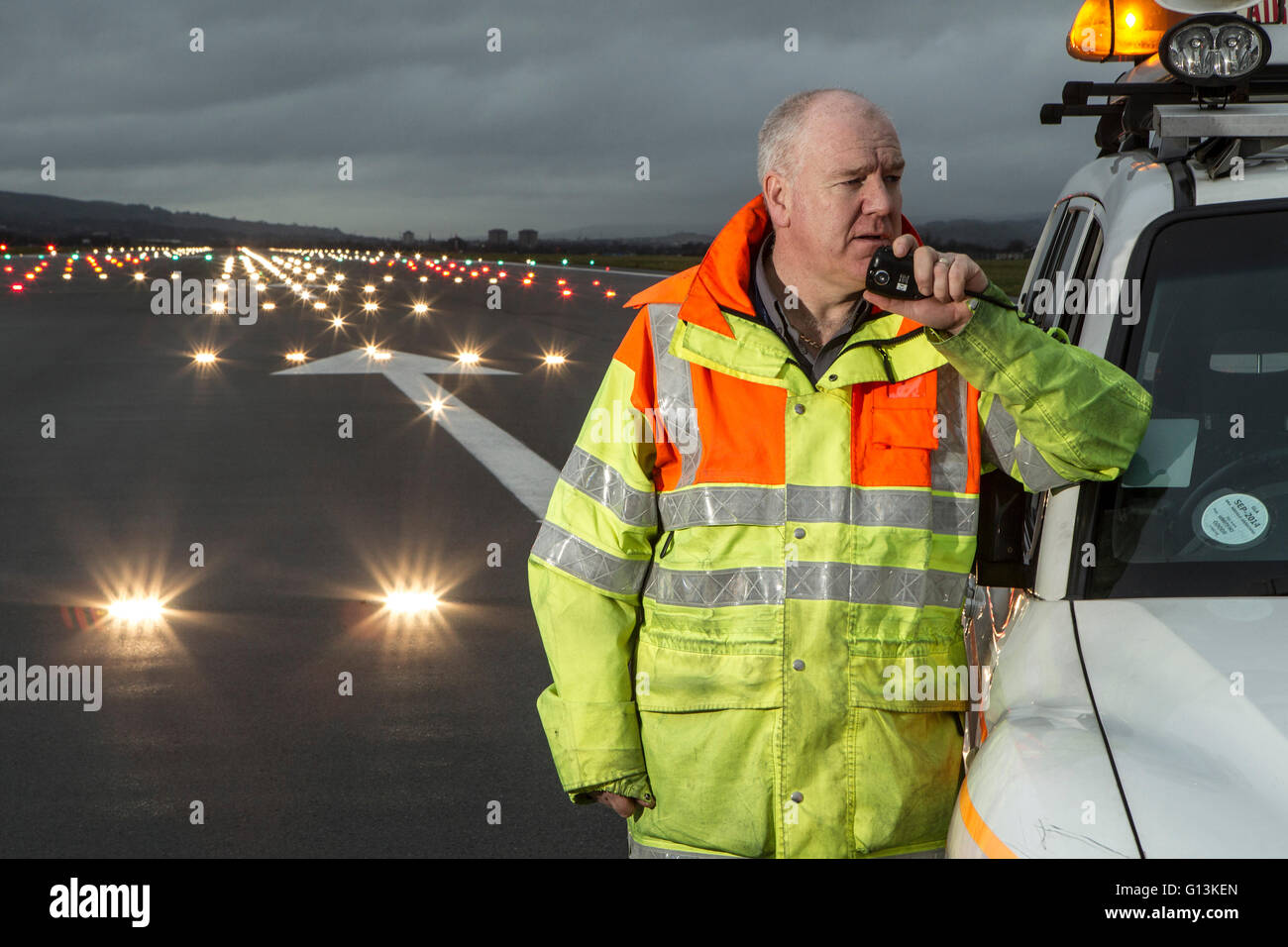 Ground Crew on runway at Glasgow Airport with landing lights in background Stock Photo