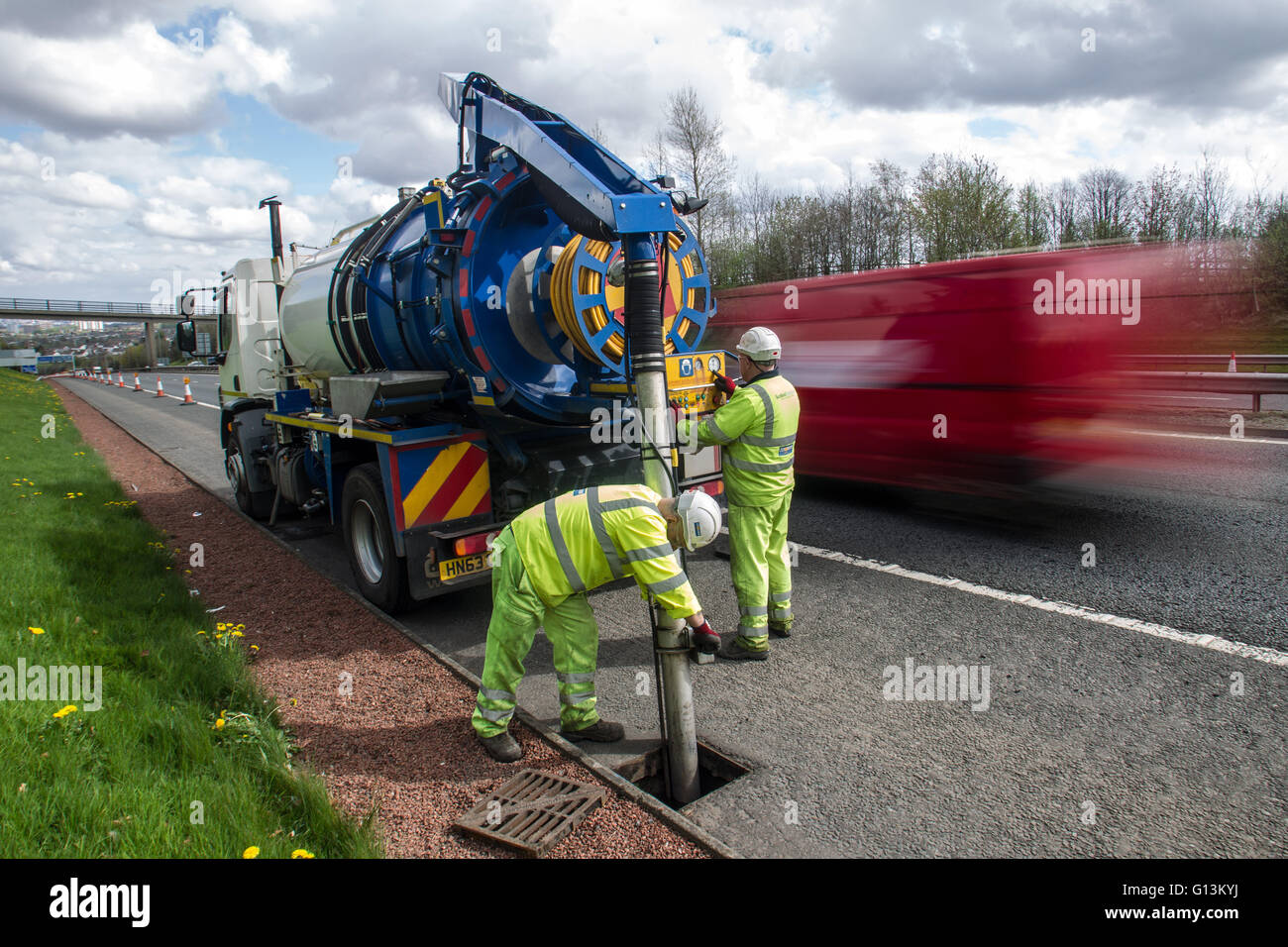 Road workers working on busy M77 with traffic passing Stock Photo