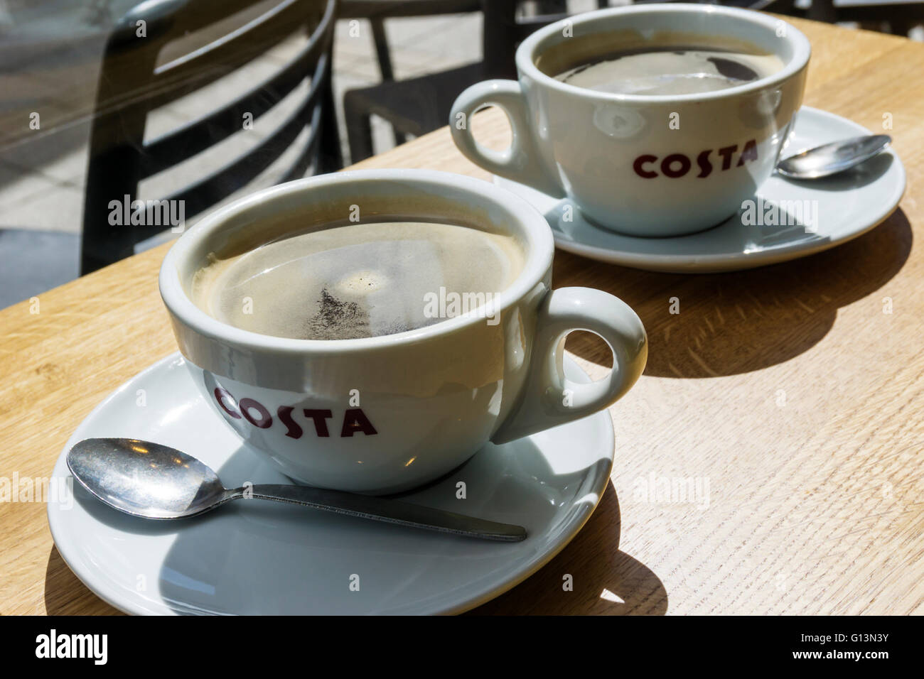 Two cups of coffee on a table in a branch of Costa.  Showing the Costa logo on the cups. The company is owned by Whitbread. Stock Photo