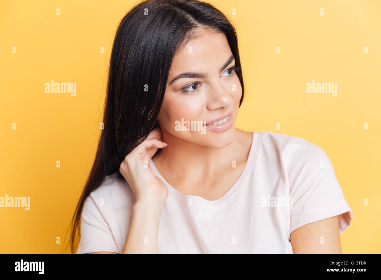 Smiling beautiful woman looking away over yellow background Stock Photo ...